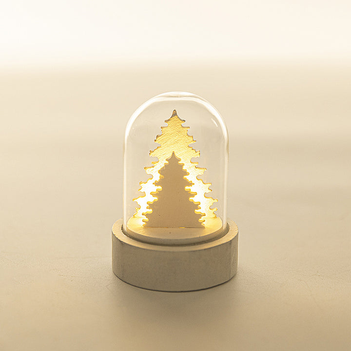 Decorative night light with a Christmas tree design inside a glass dome on a beige background