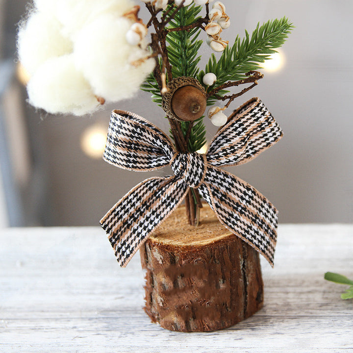 Decorative arrangement with a wooden base, greenery, cotton, and a houndstooth bow on a light background.