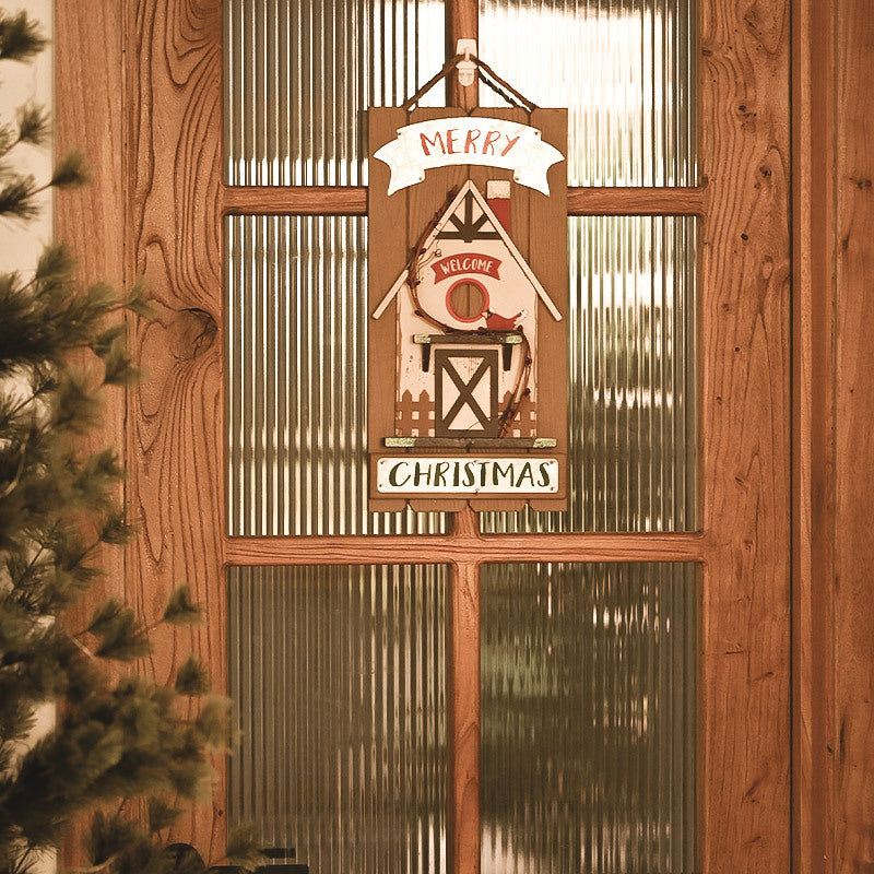 Decorative Christmas sign with a barn design hanging on a wooden door.