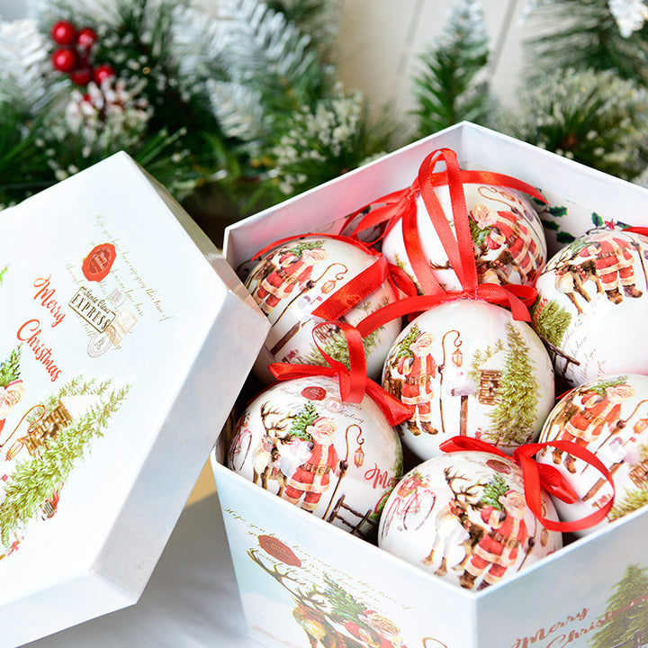 Decorative Christmas balls with red ribbons in a box, surrounded by festive greenery.