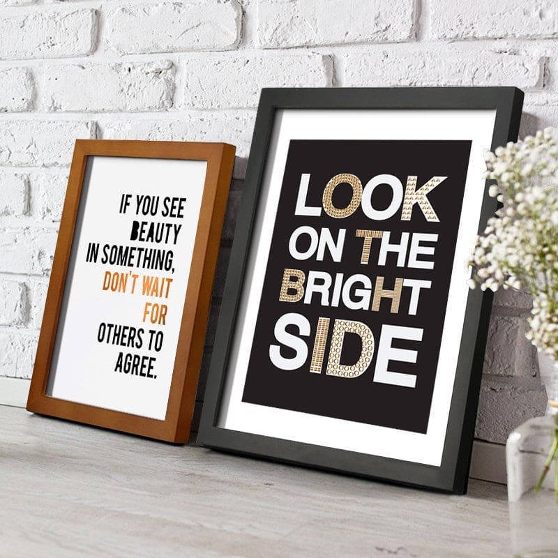 Two framed prints on a white brick wall background with motivational quotes.
