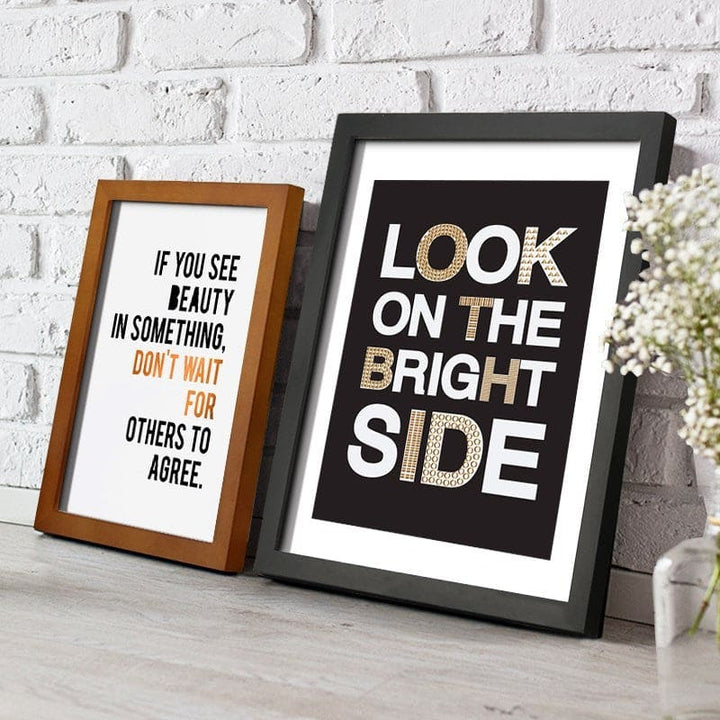 Two framed prints on a white brick wall background with motivational quotes.
