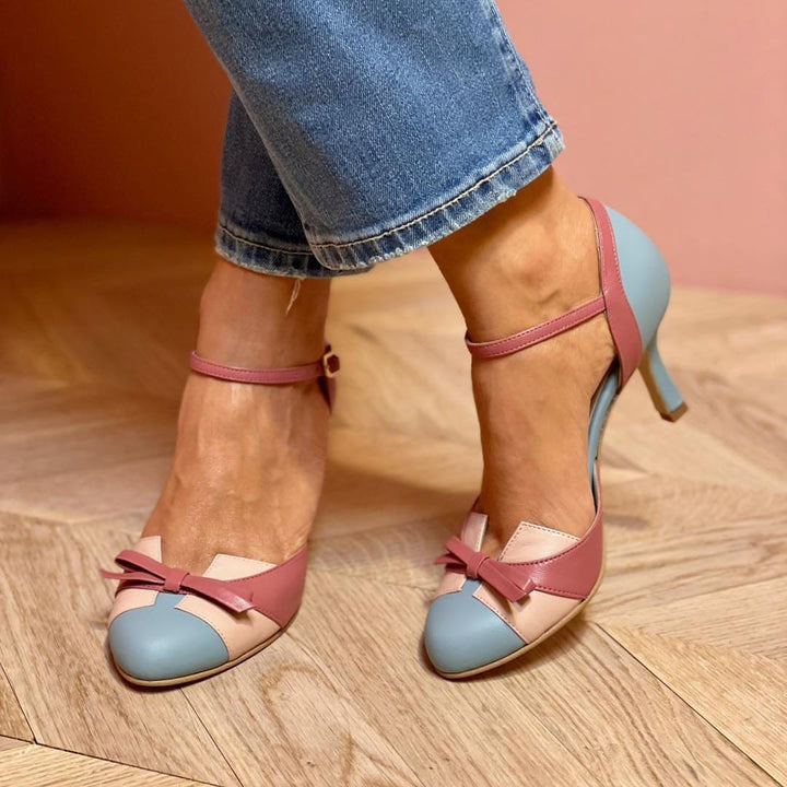 Pair of pink and blue high-heeled shoes on a wooden floor.
