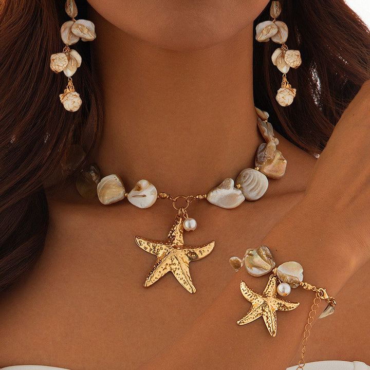Necklace and bracelet with starfish charms on a person wearing a brown top.