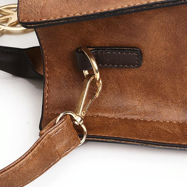 Brown leather handbag with gold hardware on a white background