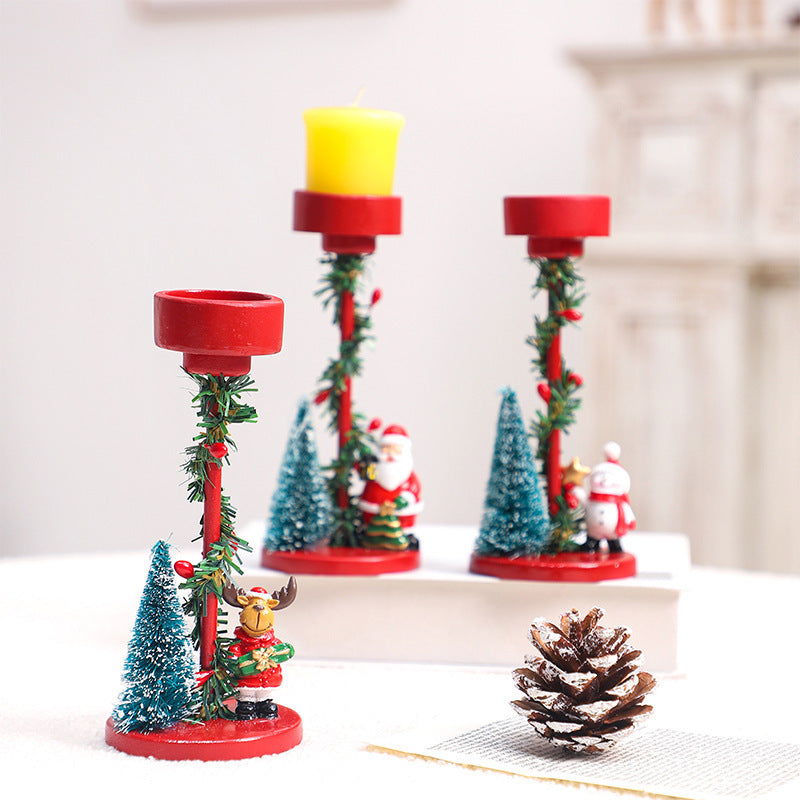 Decorative candle holders with Christmas trees and Santa Claus figures on a white surface.