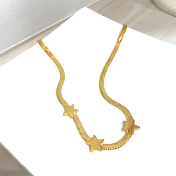 Gold necklace with star designs on a white surface