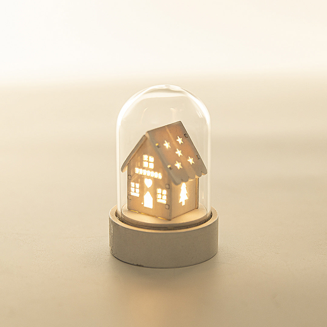 Decorative house-shaped light inside a glass dome on a beige background
