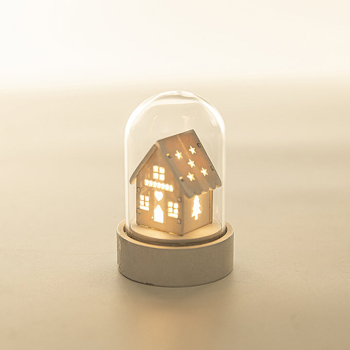 Decorative house-shaped light inside a glass dome on a beige background