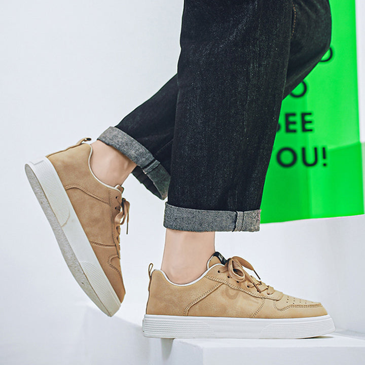 Khaki sneakers worn with dark jeans on a white background