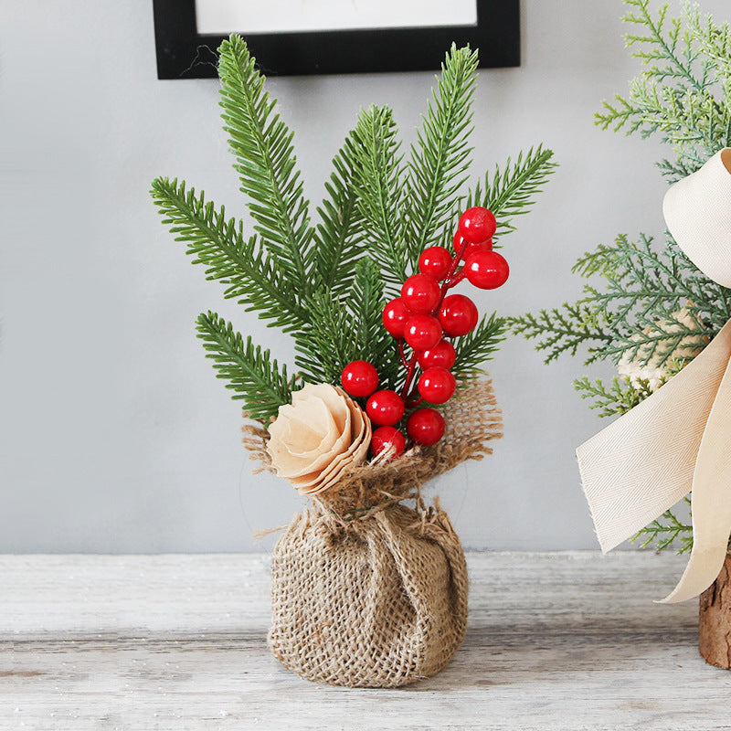 Decorative arrangement with greenery, red berries, and a beige flower on a wooden surface.