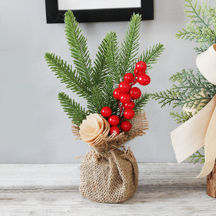 Decorative arrangement with greenery, red berries, and a beige flower on a wooden surface.