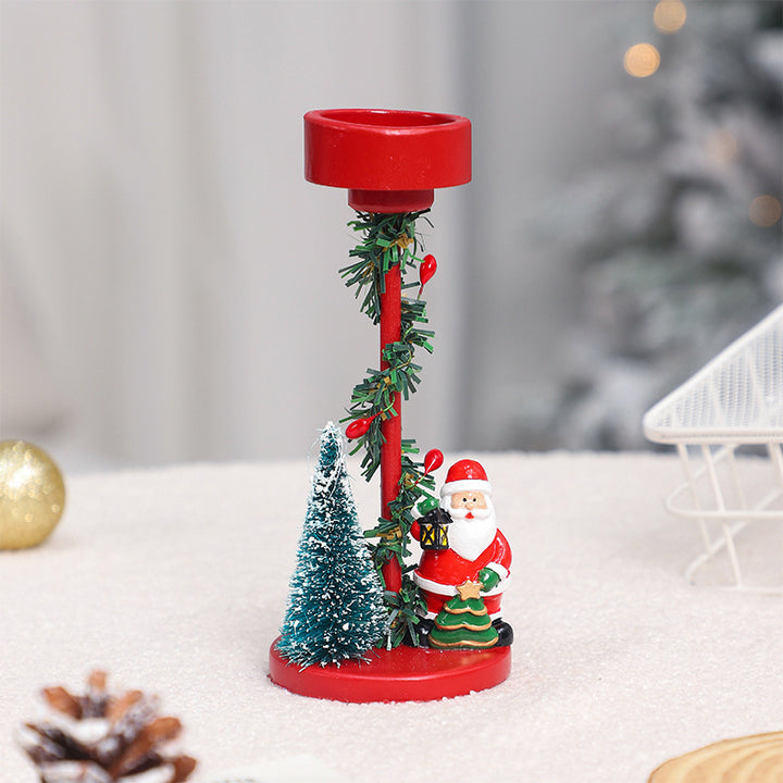 Decorative Christmas candle holder with Santa Claus figure and greenery on a white surface.