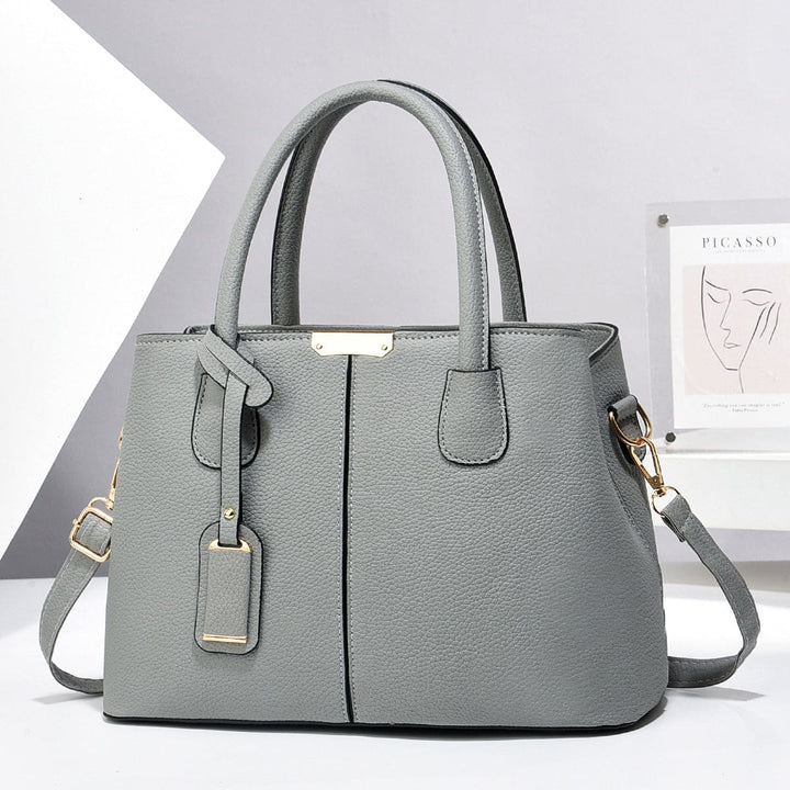 Grey handbag with gold accents on a white background