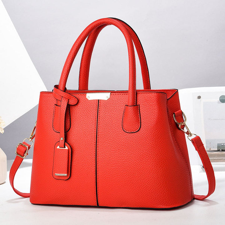 Red handbag with a strap on a light grey background