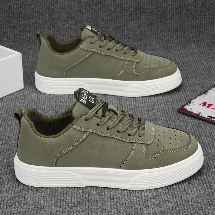 Pair of green sneakers with white soles on a grey surface