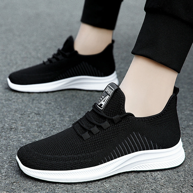 Black fashion sneakers with white soles worn by a person on a grey surface | Confetti Living