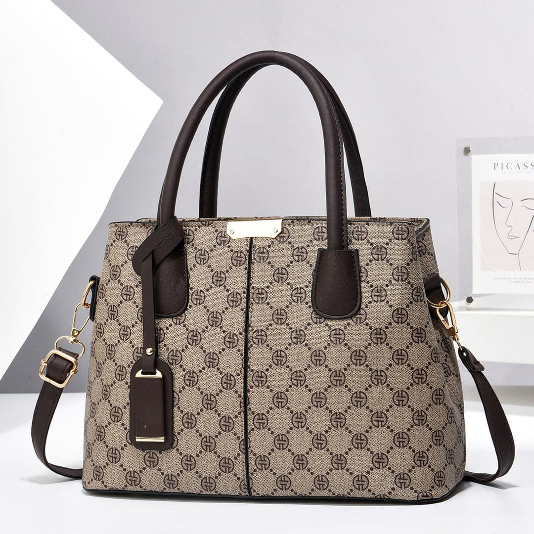 Patterned beige brown handbag with brown handles and strap on a light gray background