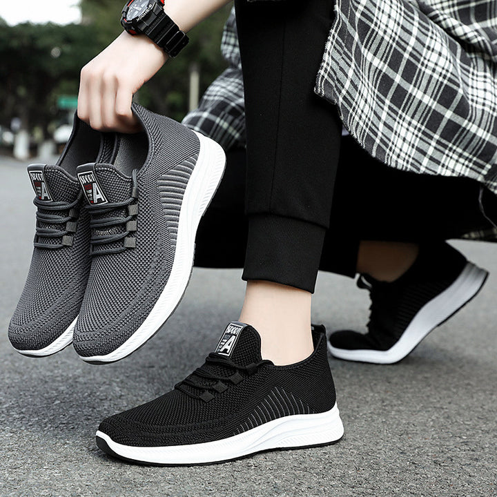 Person wearing black fashion sneakers, holding grey fashion sneakers in a street setting | Confetti Living