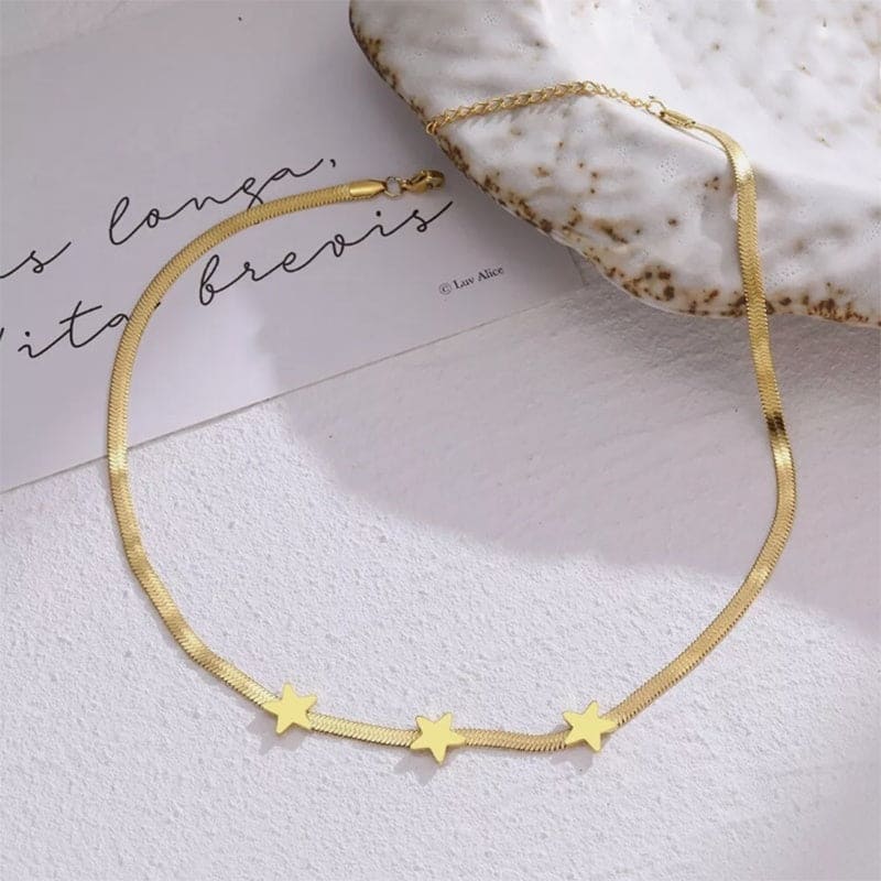 Gold necklace with star pendants on a white surface