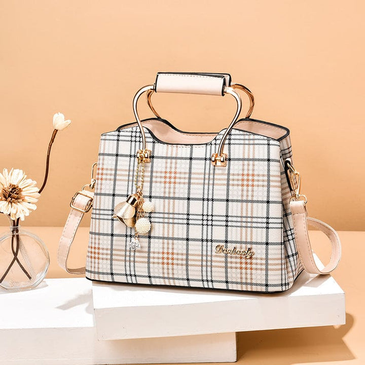 Plaid handbag with gold accents on a beige background