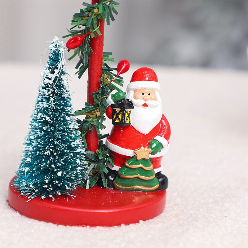 Decorative Christmas scene with Santa Claus, trees, and a lantern on a white background