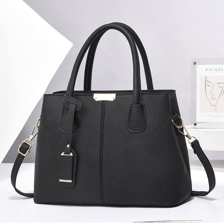 Black handbag with gold accents on a white background