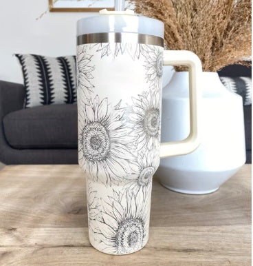White tumbler with black floral design on a wooden table.