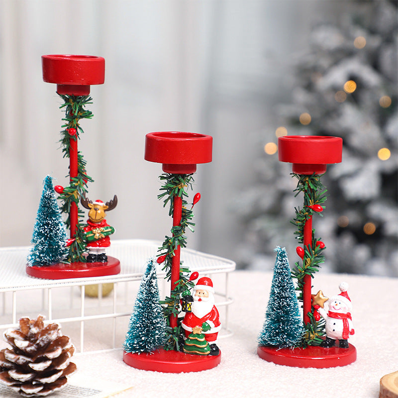 Decorative candle holders with Christmas-themed figurines on a white surface.
