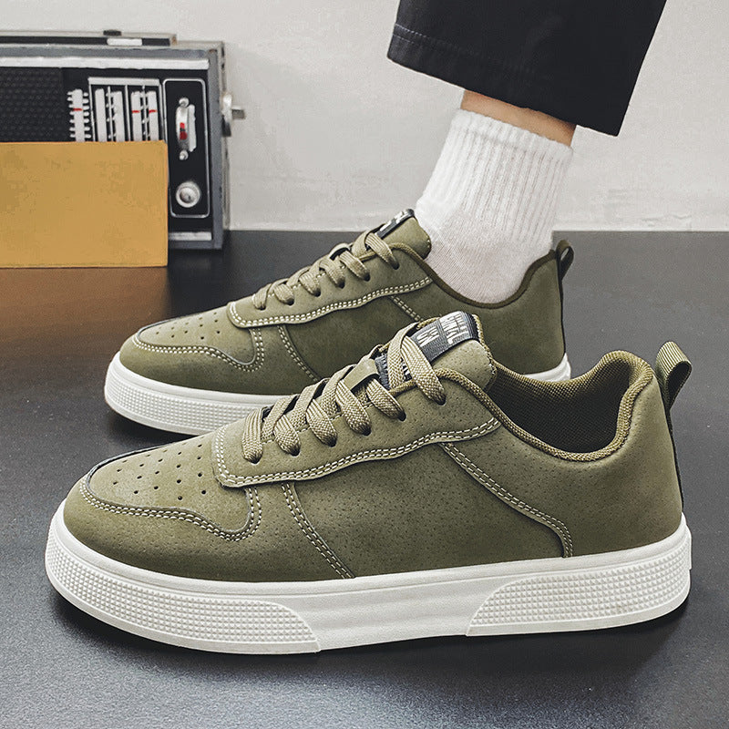 Green sneakers with white soles worn by a person on a grey surface.